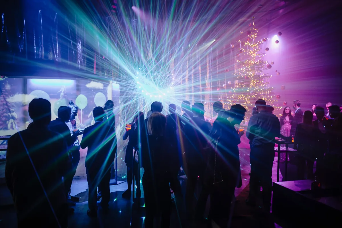 Eventfotografie: Partygäste mit Lasern und beleuchtetem Weihnachtsbaum