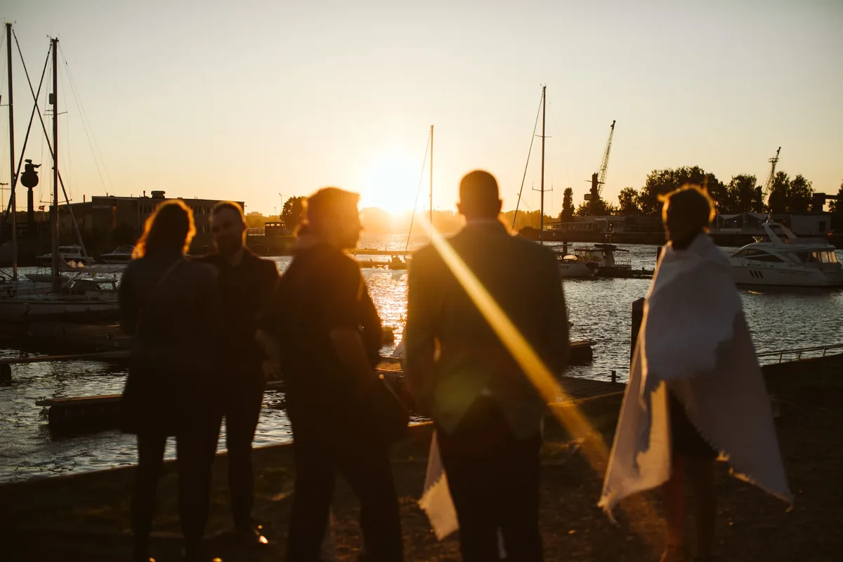 Gäste im Gegenlicht des Sonnenuntergangs am Hafen beim Firmenevent