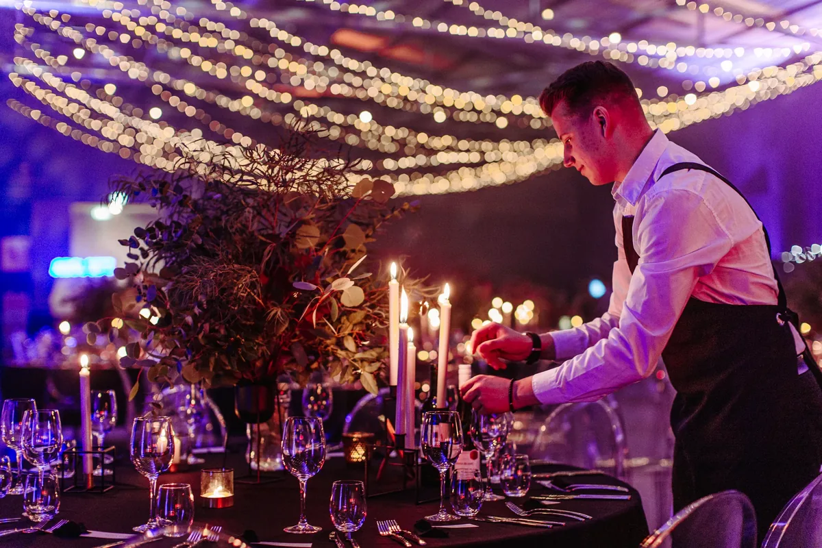 Kellner zündet Kerzen am festlich gedeckten Tisch an – Eventfotografie