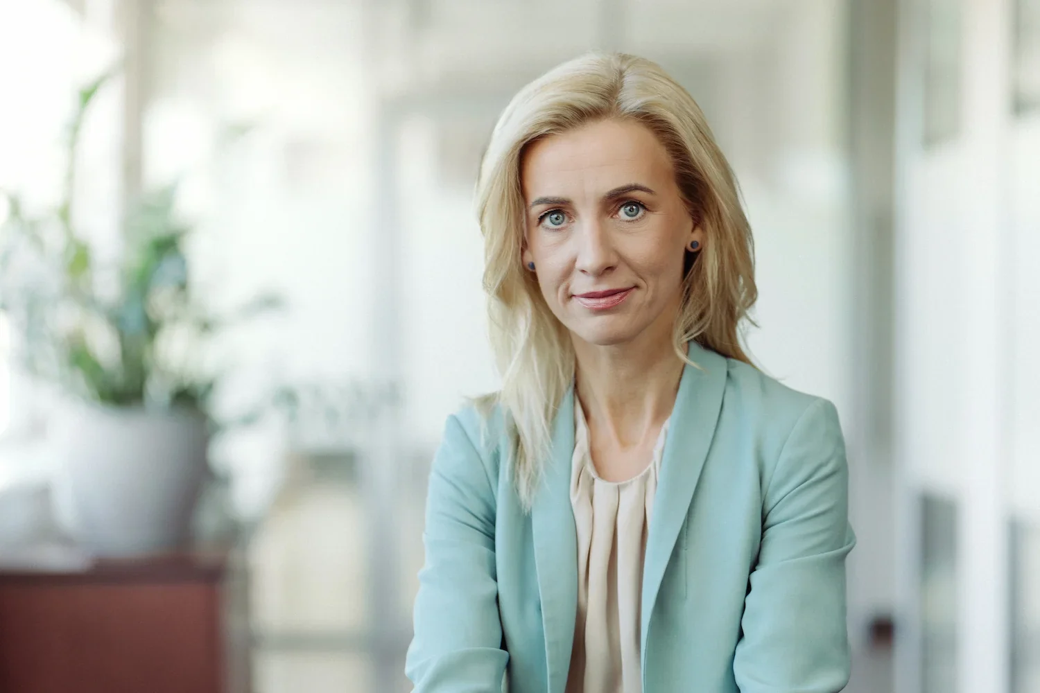 Business-Porträt einer Frau im schwarzen Blazer mit verschränkten Armen vor dunklem Hintergrund